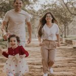 Smiling family enjoys a playful walk in a São Paulo park during a sunny day.