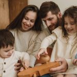 A joyful family of four playing together with a wooden toy indoors. Captures warmth and togetherness.