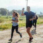 A group of runners enjoys a vibrant morning jog on a rural dirt road.